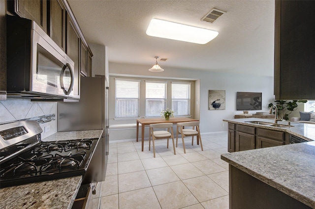 2831 Lake Villa Dr, Missouri City, TX 77459 - kitchen with a sink, appliances with stainless steel finishes, dark brown cabinets, baseboards, and a textured ceiling