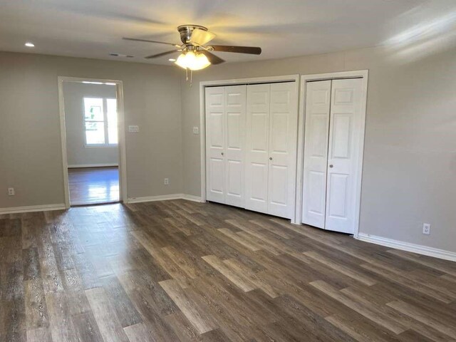 7209 La Salette St, Houston, TX 77021 - unfurnished bedroom with dark wood-style floors, two closets, baseboards, and ceiling fan
