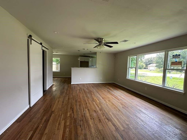 7209 La Salette St, Houston, TX 77021 - empty room featuring a barn door, baseboards, dark wood-type flooring, and ceiling fan