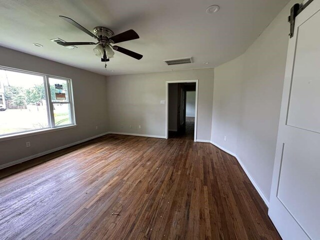 7209 La Salette St, Houston, TX 77021 - spare room featuring dark wood finished floors, a ceiling fan, baseboards, and a barn door