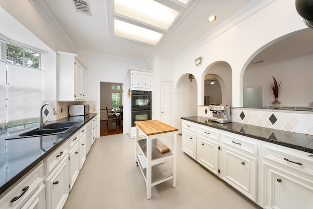 4910 Glen Hollow St, Sugar Land, TX 77479 - kitchen featuring a sink, decorative backsplash, white cabinets, healthy amount of natural light, and ornamental molding