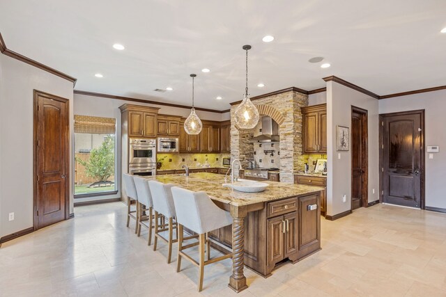 2919 Auburn Path, Sugar Land, TX 77479 - kitchen featuring appliances with stainless steel finishes, wall chimney range hood, decorative backsplash, brown cabinetry, and a breakfast bar area