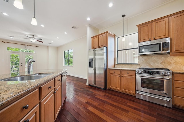415 Tuam St, Houston, TX 77006 - kitchen with stainless steel appliances, a sink, brown cabinetry, crown molding, and recessed lighting