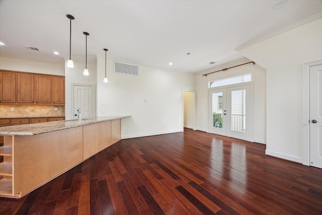 415 Tuam St, Houston, TX 77006 - kitchen featuring dark wood-type flooring, light stone counters, ornamental molding, backsplash, and brown cabinets