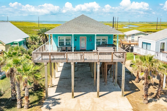 12881 Coronado Dr, Freeport, TX 77541 - coastal home featuring a carport, a shingled roof, a wooden deck, and dirt driveway