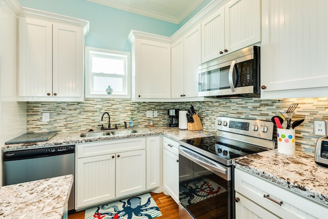 12881 Coronado Dr, Freeport, TX 77541 - kitchen featuring appliances with stainless steel finishes, a sink, white cabinets, crown molding, and backsplash