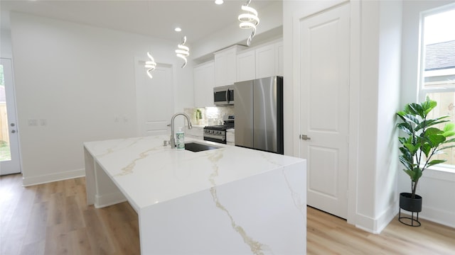 7805 Avenue Ave E, Houston, TX 77012 - kitchen featuring appliances with stainless steel finishes, a sink, light wood-type flooring, an island with sink, and decorative backsplash