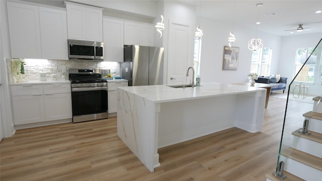 7805 Avenue Ave E, Houston, TX 77012 - kitchen featuring appliances with stainless steel finishes, a sink, open floor plan, light wood-style floors, and recessed lighting