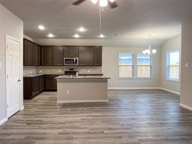 27315 Blue Pool Dr, Katy, TX 77493 - kitchen featuring stainless steel appliances, vaulted ceiling, wood finished floors, decorative backsplash, and a chandelier