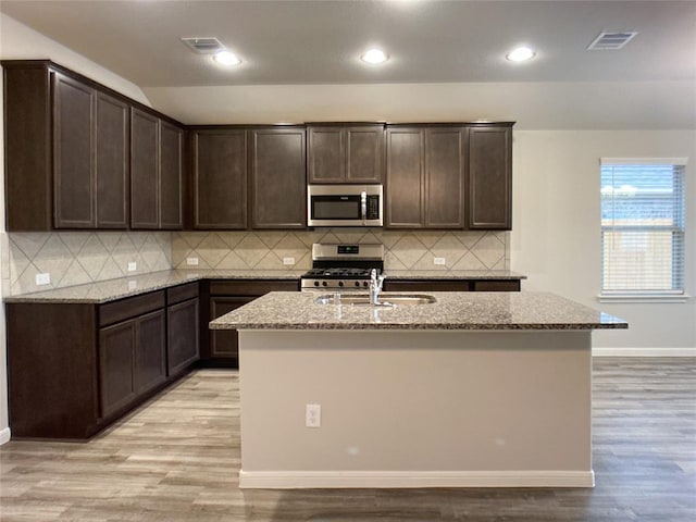 27315 Blue Pool Dr, Katy, TX 77493 - kitchen with stainless steel appliances, a sink, light stone counters, dark brown cabinetry, and recessed lighting