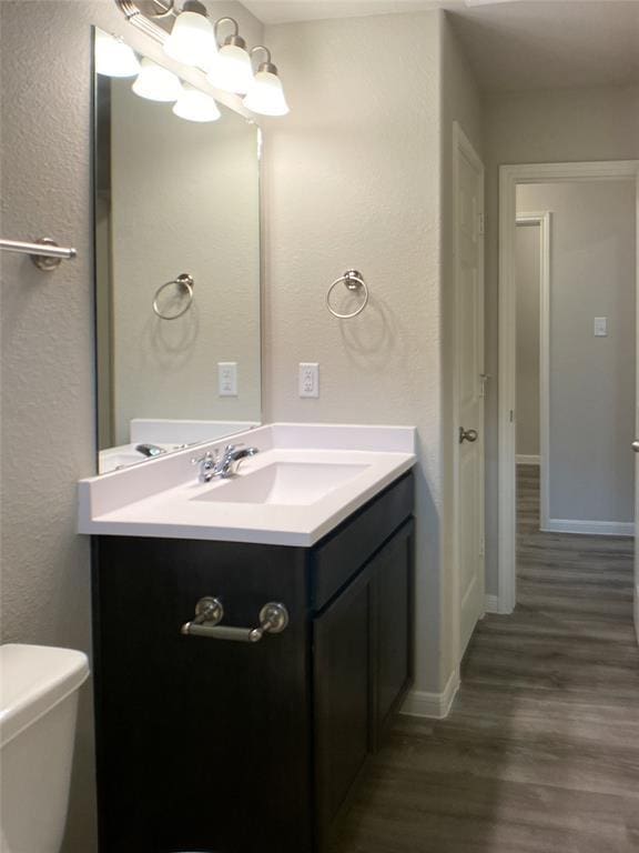 27315 Blue Pool Dr, Katy, TX 77493 - bathroom featuring wood finished floors, vanity, baseboards, a textured wall, and toilet