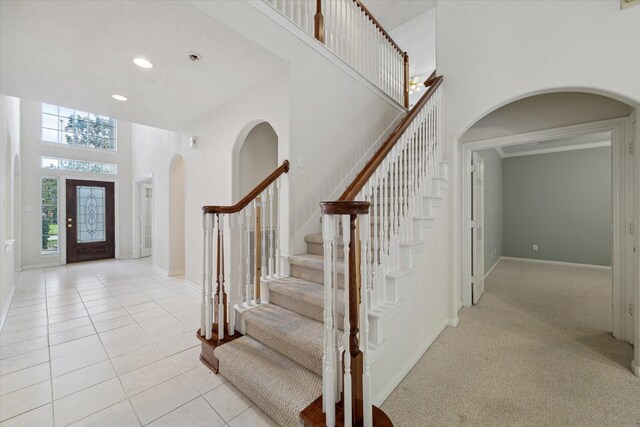 5111 Maple Hill Trl, Houston, TX 77345 - foyer entrance featuring a high ceiling, arched walkways, stairway, baseboards, and light tile patterned floors