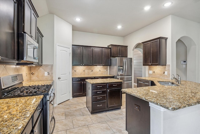 5332 Pointe Spring Xing, Spring, TX 77389 - kitchen featuring appliances with stainless steel finishes, a sink, arched walkways, light stone counters, and backsplash