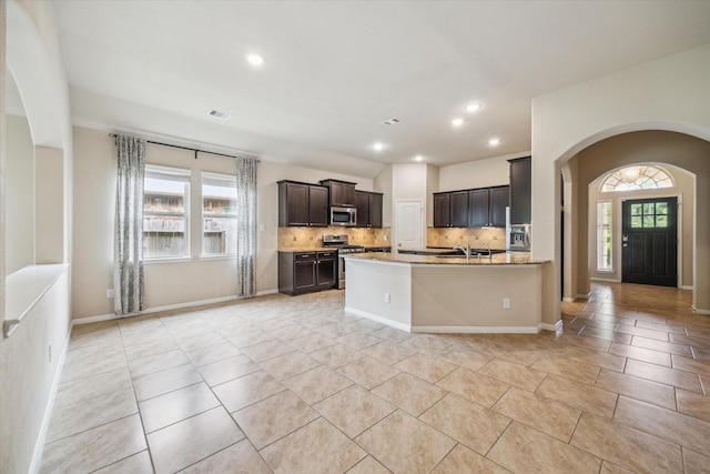 5332 Pointe Spring Xing, Spring, TX 77389 - kitchen with stainless steel appliances, light tile patterned floors, arched walkways, backsplash, and dark brown cabinets