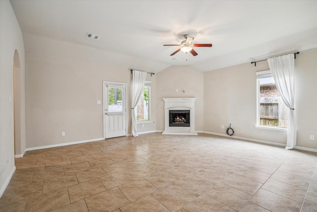 5332 Pointe Spring Xing, Spring, TX 77389 - unfurnished living room with arched walkways, a ceiling fan, a fireplace with raised hearth, baseboards, and vaulted ceiling