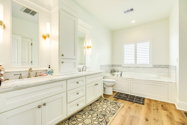 998 Austin Dr, Gilchrist, TX 77617 - bathroom with wood finished floors, double vanity, a bath, and toilet
