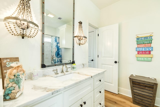 998 Austin Dr, Gilchrist, TX 77617 - full bath with wood finished floors, a chandelier, vanity, a shower with shower curtain, and baseboards