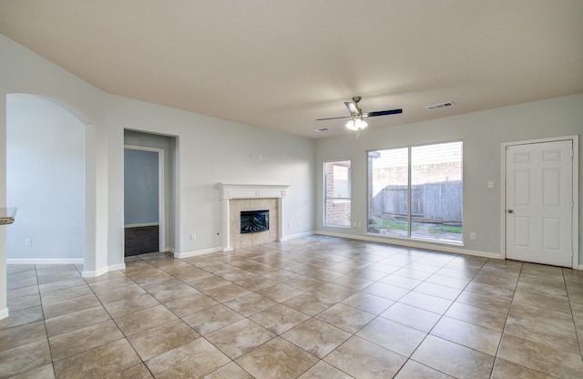 14814 Bridle Bend Dr, Houston, TX 77084 - unfurnished living room with a ceiling fan, a fireplace, light tile patterned flooring, arched walkways, and baseboards