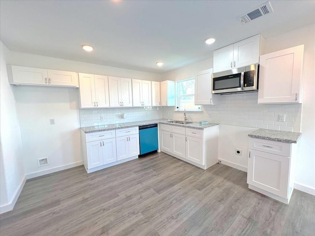 6309 Sandra St, Houston, TX 77028 - kitchen with stainless steel microwave, dishwashing machine, a sink, white cabinetry, and recessed lighting