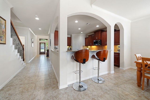 4307 Countrypines Dr, Spring, TX 77388 - kitchen featuring stainless steel microwave, ornamental molding, light tile patterned floors, a breakfast bar, and backsplash