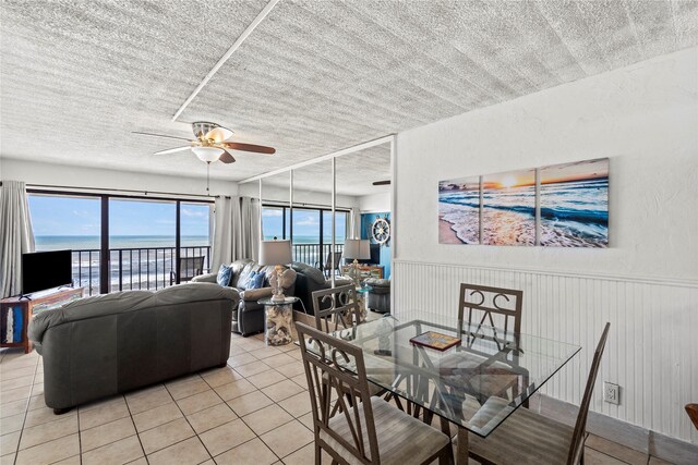7310 Seawall Blvd Unit 707, Galveston, TX 77551 - dining room featuring light tile patterned floors, a textured ceiling, ceiling fan, and wainscoting