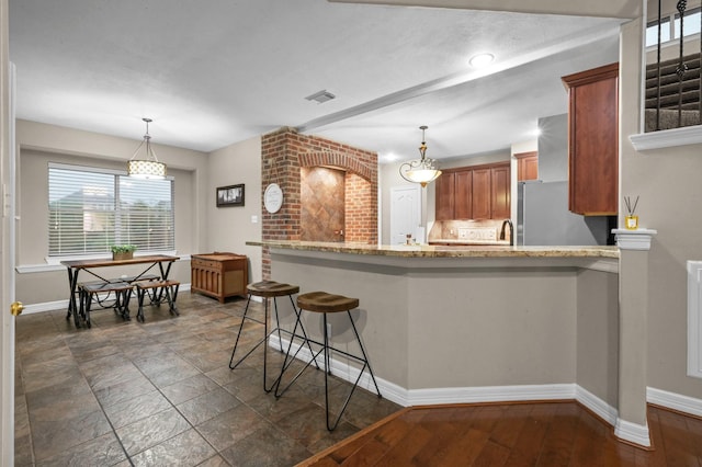 19634 Stone Lake Dr, Tomball, TX 77377 - kitchen featuring freestanding refrigerator, baseboards, a peninsula, brown cabinetry, and light stone countertops