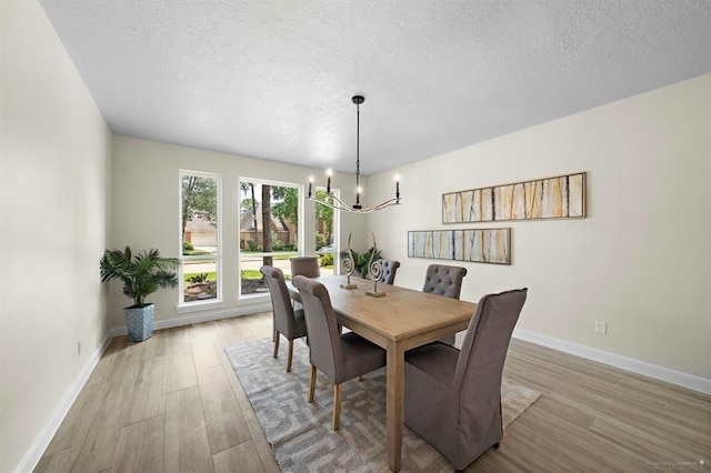 8002 Oxfordshire Dr, Spring, TX 77379 - dining room featuring a chandelier, wood finished floors, baseboards, and a textured ceiling