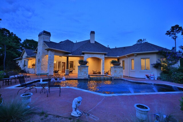 9502 Clubhouse Cir, Magnolia, TX 77354 - rear view of house featuring stucco siding, stone siding, a chimney, a patio area, and roof with shingles