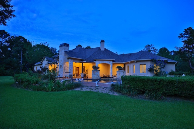 9502 Clubhouse Cir, Magnolia, TX 77354 - back of property at dusk with a chimney, a lawn, and stucco siding