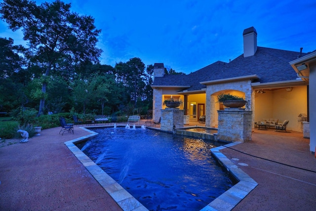 9502 Clubhouse Cir, Magnolia, TX 77354 - pool at dusk with a patio area, an outdoor stone fireplace, and a pool with connected hot tub