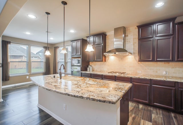 27326 Pendleton Trace Dr, Spring, TX 77386 - kitchen with wall chimney range hood, appliances with stainless steel finishes, dark wood-style flooring, baseboards, and a center island with sink