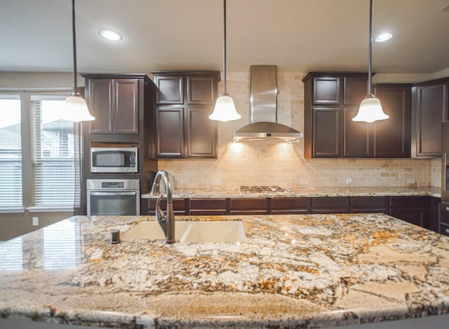 27326 Pendleton Trace Dr, Spring, TX 77386 - kitchen with stainless steel appliances, wall chimney exhaust hood, dark brown cabinetry, a sink, and decorative backsplash