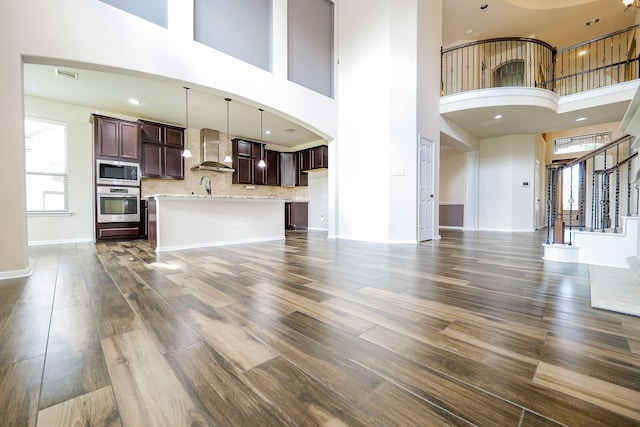 27326 Pendleton Trace Dr, Spring, TX 77386 - unfurnished living room featuring a high ceiling, dark wood-style flooring, stairs, a sink, and baseboards