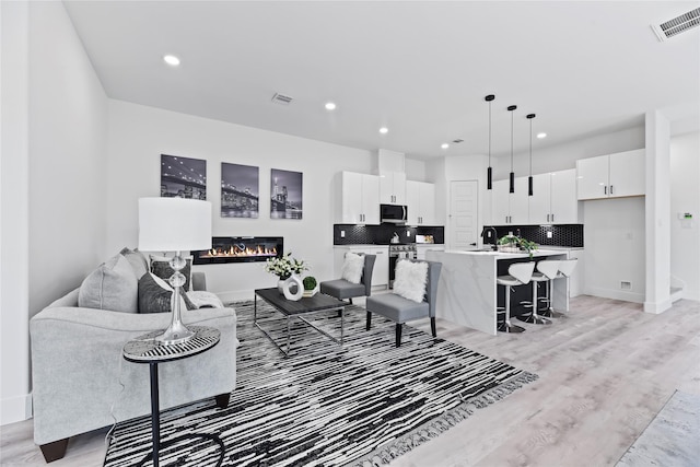7212 England St, Houston, TX 77021 - living area featuring light wood-style flooring, a glass covered fireplace, recessed lighting, and baseboards