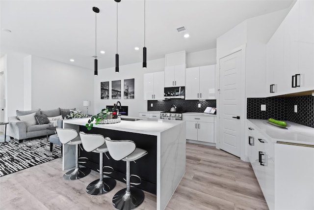 7212 England St, Houston, TX 77021 - kitchen featuring stainless steel appliances, light wood-style flooring, a sink, white cabinets, and recessed lighting