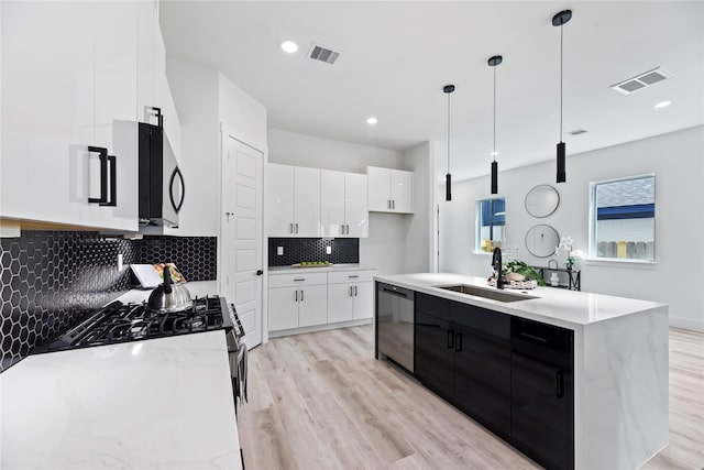 7212 England St, Houston, TX 77021 - kitchen with dishwasher, a sink, light wood-style floors, white cabinetry, and recessed lighting