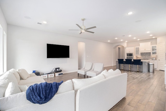 9311 Crescent Mill Dr, Missouri City, TX 77459 - living area with arched walkways, ceiling fan, light wood-style floors, recessed lighting, and baseboards