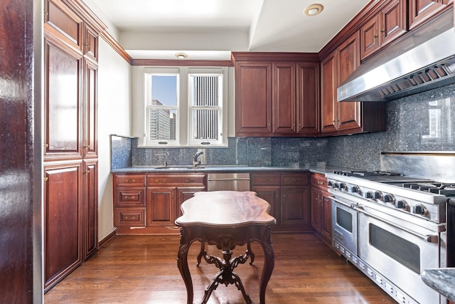1700 Main St Unit 7B, Houston, TX 77002 - kitchen with appliances with stainless steel finishes, under cabinet range hood, backsplash, dark countertops, and dark wood-type flooring