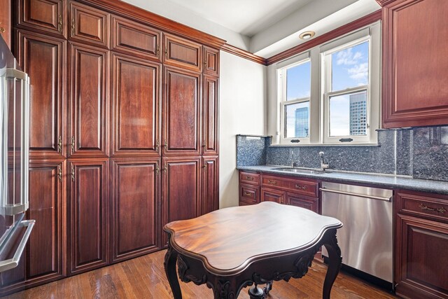 1700 Main St Unit 7B, Houston, TX 77002 - kitchen with appliances with stainless steel finishes, reddish brown cabinets, a sink, dark countertops, and dark wood-type flooring