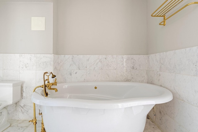 1700 Main St Unit 7B, Houston, TX 77002 - full bathroom with a freestanding bath, toilet, tile walls, a wainscoted wall, and marble finish flooring