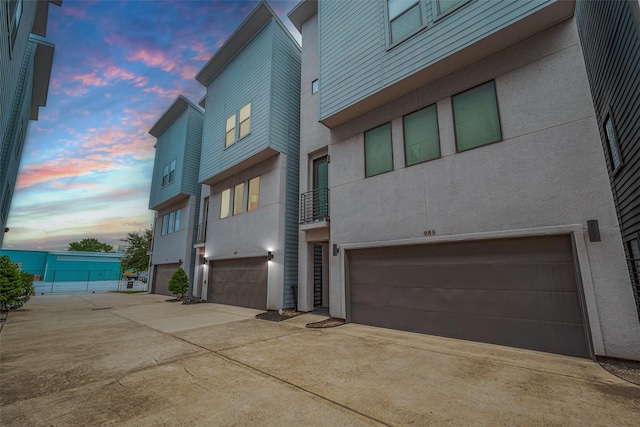953 Saint Augustine St, Houston, TX 77023 - back of property at dusk with a garage, stucco siding, and concrete driveway