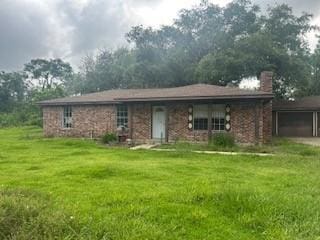 20250 County Road 510q, Brazoria, TX 77422 - view of front of house featuring a chimney, a front lawn, and a garage