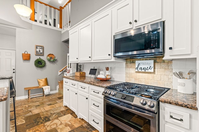 12596 Point Aquarius Blvd, Willis, TX 77318 - kitchen featuring appliances with stainless steel finishes, backsplash, light stone finish floors, white cabinets, and baseboards