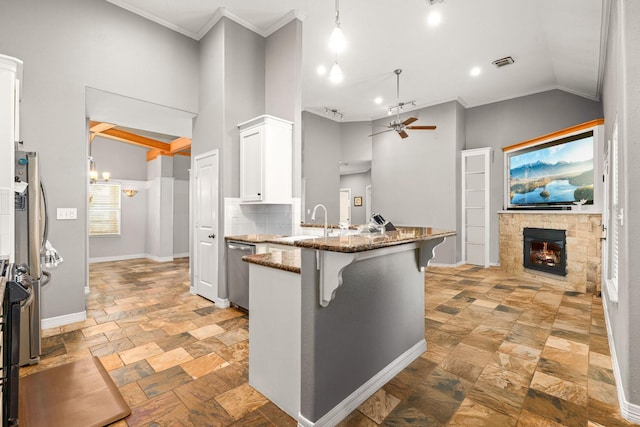 12596 Point Aquarius Blvd, Willis, TX 77318 - kitchen featuring stainless steel dishwasher, ceiling fan, a stone fireplace, a peninsula, and a sink