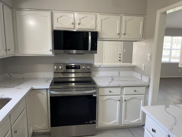 8315 Marble Arch Ct, Humble, TX 77338 - kitchen with stainless steel appliances, white cabinetry, and light stone countertops