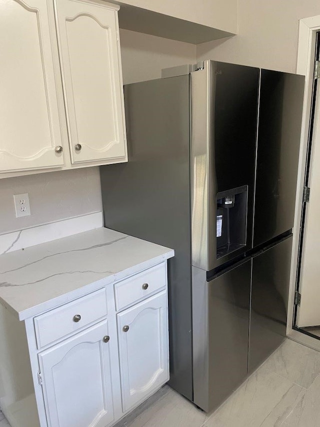 8315 Marble Arch Ct, Humble, TX 77338 - kitchen featuring stainless steel fridge, light stone counters, white cabinetry, and light marble finish flooring