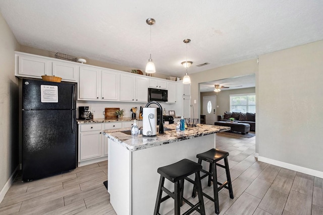 715 S Nugent St, La Porte, TX 77571 - kitchen featuring black appliances, wood tiled floors, baseboards, white cabinetry, and light stone countertops