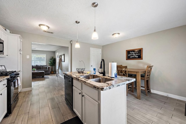 715 S Nugent St, La Porte, TX 77571 - kitchen featuring black appliances, a sink, wood tiled floors, light stone counters, and baseboards