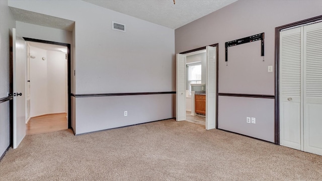 23938 Spring Way Dr, Spring, TX 77373 - unfurnished bedroom featuring carpet flooring, a closet, ensuite bathroom, and a textured ceiling