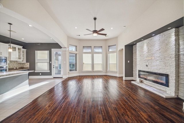 7930 Rippling Stream Ln, Richmond, TX 77407 - unfurnished living room featuring ceiling fan, arched walkways, a fireplace, hardwood / wood-style flooring, and recessed lighting